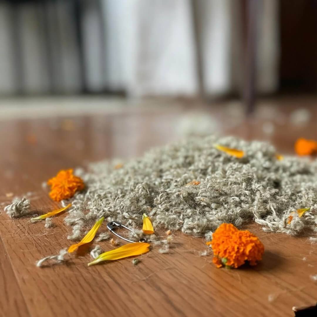 7 Eco-Friendly Fabrics You Should Know About Blurry hemp and cotton scraps with marigolds, bent pin.